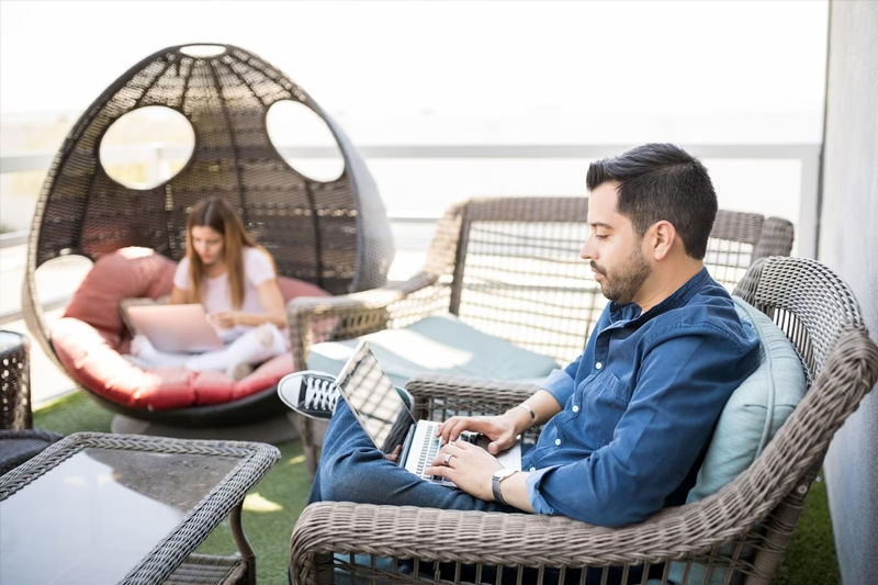 coppia in vacanza che lavora al pc comodamente in giardino