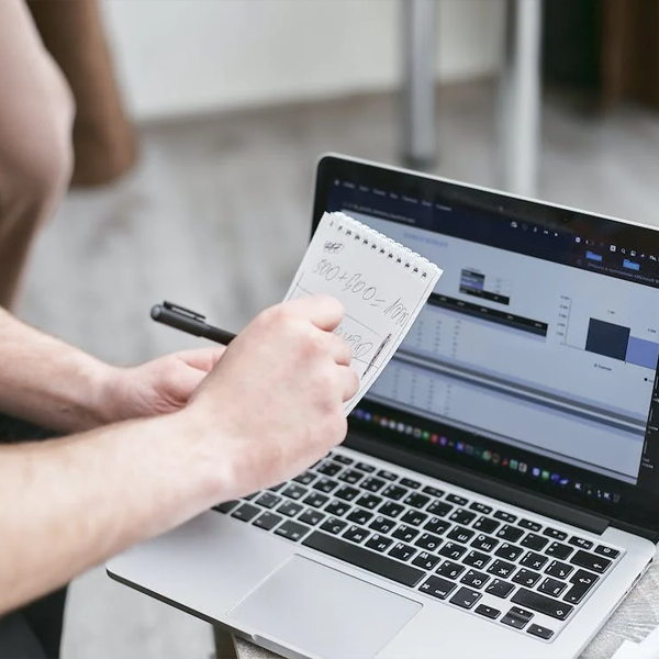 dettaglio di persona che prende appunti avanti a un pc